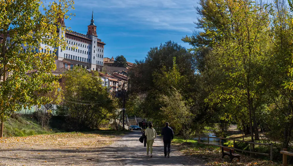 Dos personas pasean a la orilla del rio Turia a su paso por Teruel este domingo