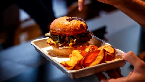 Una persona sostiene una hamburguesa en una bandeja durante la presentación de las novedades de los actos de entrega de la 34ª edición de los Premios Rei Jaume I 2022, en el Restaurante Hamburguesería Hundred, a 7 de noviembre de 2022, en Valencia