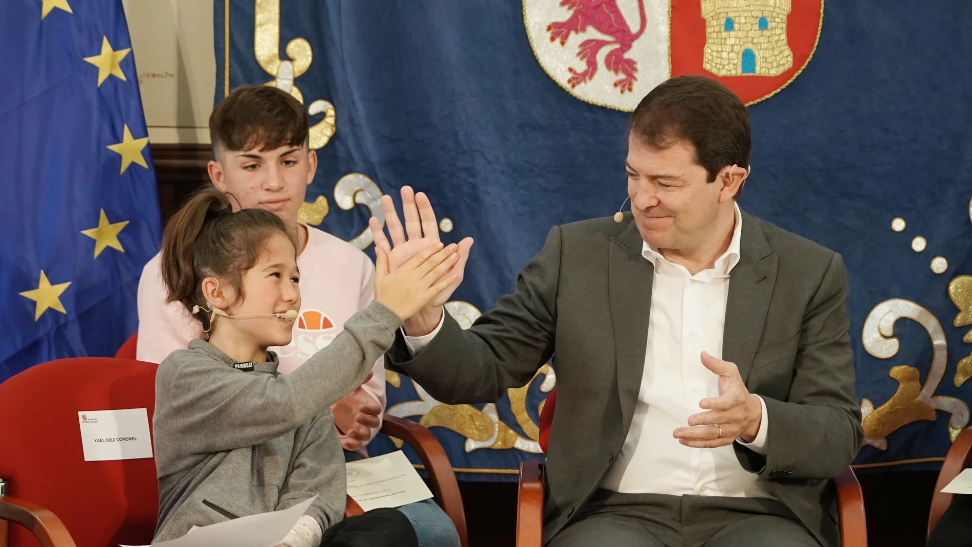 Fernández Mañueco choca las manos con una joven miembro del Foro de Participación de la Infancia y la Adolescencia de Castilla y León