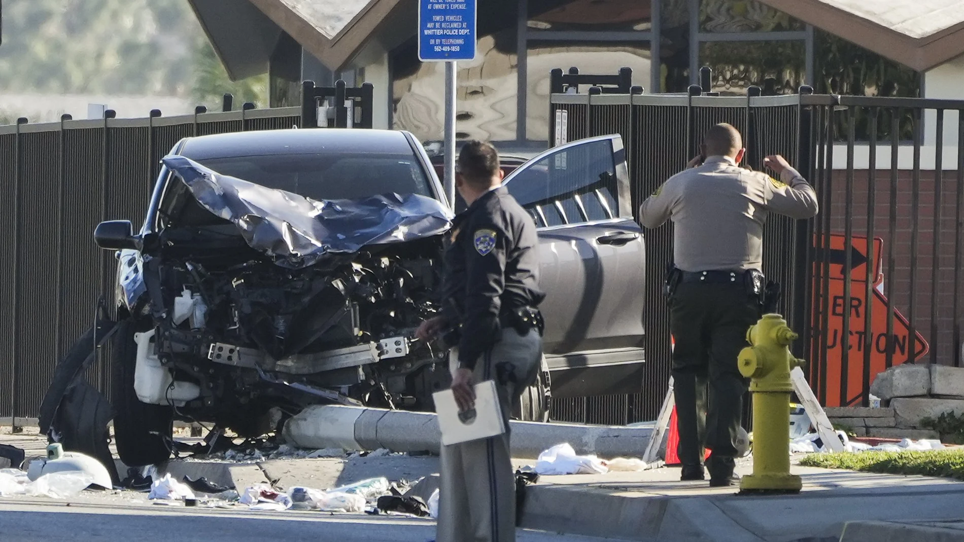 Dos agentes se detienen junto a un vehículo SUV destrozado que golpeó a los reclutas del alguacil del condado de Los Ángeles en Whittier