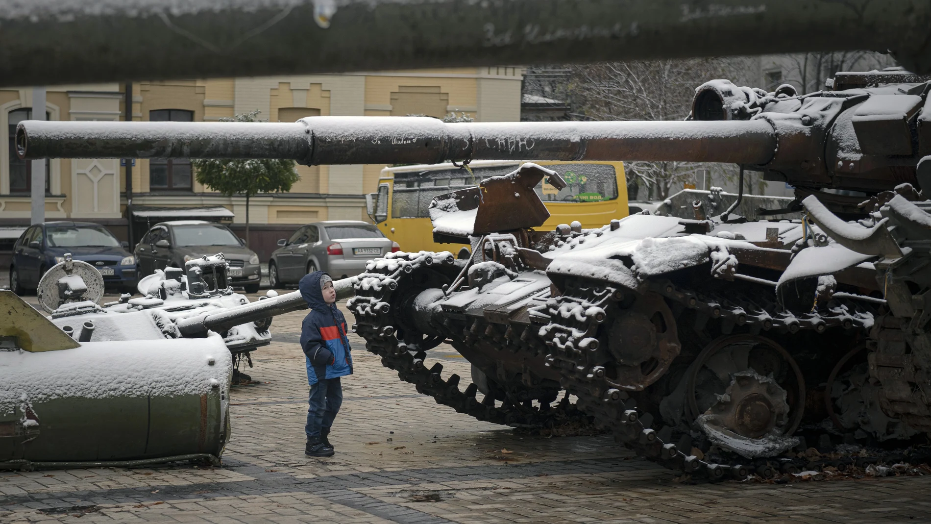 Un niño observa tanques dejados por Rusia en medio de la nieva en Kyiv