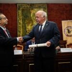 El presidente de la Cofradía Gastronómica del Rabo de Toro Cordobés, Ricardo Rojas (i), hace entrega al presidente del Parlamento de Andalucía, Jesús Aguirre, de la insignia y el diploma como cofrade de honor de esta hermandad