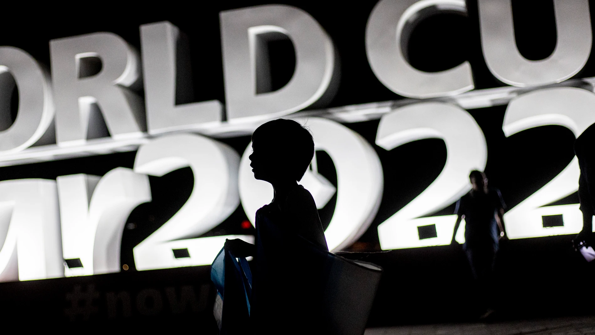 Un niño camina en Doha frente a un cartel del Mundial de Qatar