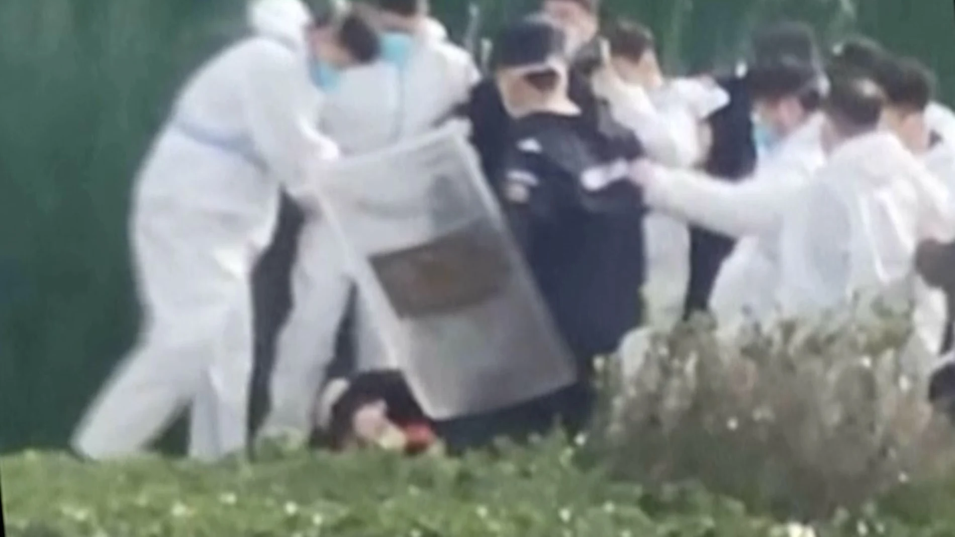 Personal de seguridad con ropa protectora rodea y patea a un manifestante después de que éste agarrara un poste de metal que había sido utilizado para golpearlo durante la protesta en el complejo de la fábrica operada por Foxconn Technology Group, que dirige la mayor fábrica de iPhone de Apple del mundo en Zhengzhou
