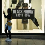Varias personas pasan por delante de los comercios que anuncian los descuentos del "Black Friday", a 23 de noviembre de 2022, en Madrid