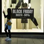 Varias personas pasan por delante de los comercios que anuncian los descuentos del &quot;Black Friday&quot;, a 23 de noviembre de 2022, en Madrid