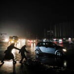 Habitantes de Kyiv cruzan a oscuras una calle de la capital ucraniana iluminada por los faros de los automóviles