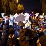 Manifestantes agitan hojas de papel en blanco durante una protesta en Pekín, China