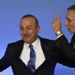 El secretario general de la OTAN Jens Stoltenberg, coge al ministro de Exteriores turco, Mevlut Cavusoglu antes de la foto de familia en la cumbre de Bucarest (Rumanía)
