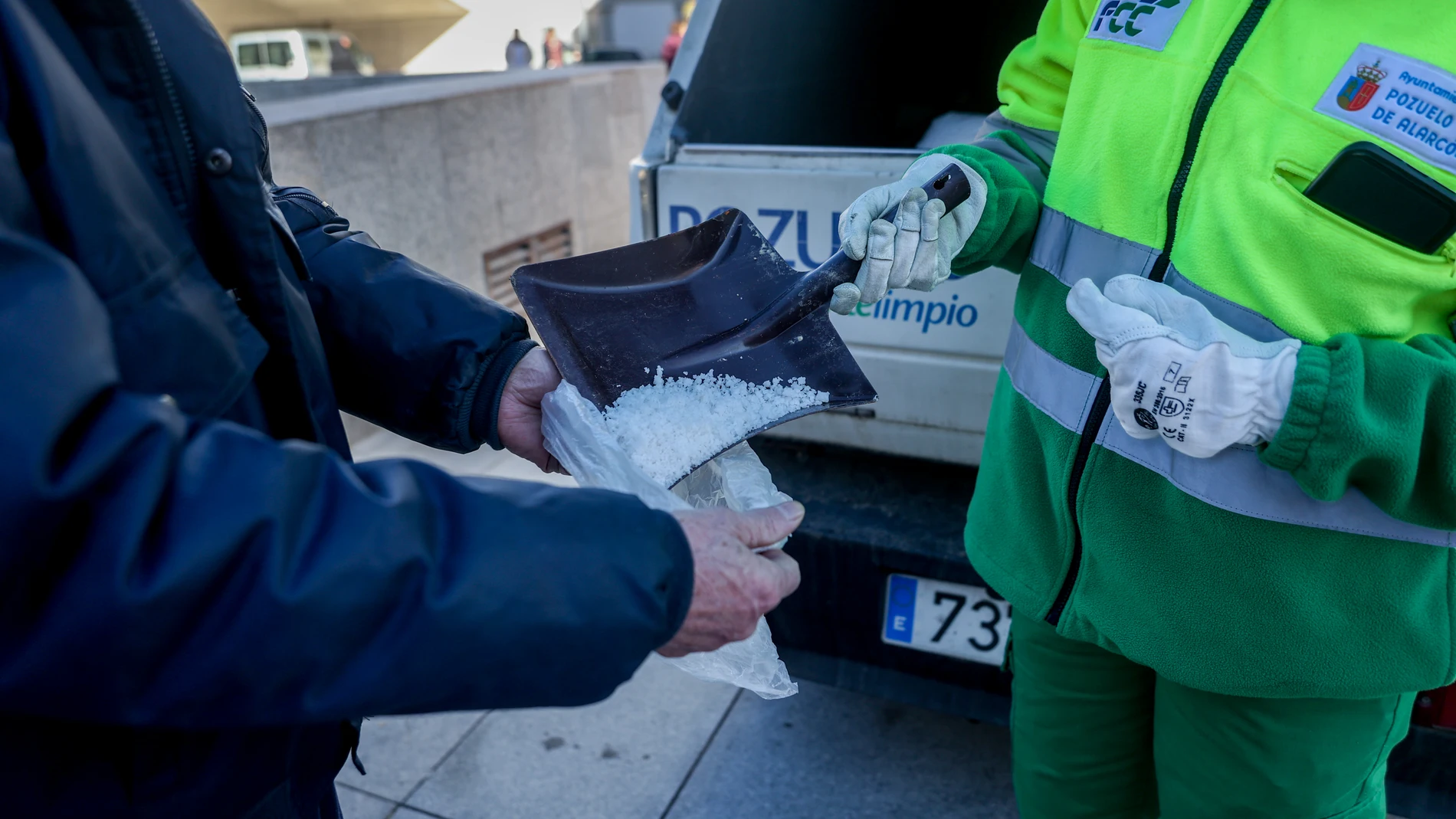 Una persona dando sal a un vecino en la campaña de entrega de sal de Pozuelo de Alarcón (Madrid)