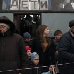 Ucranianos de Mariupol se bajan de un autobús en el que se puede leer en ruso: "niños"