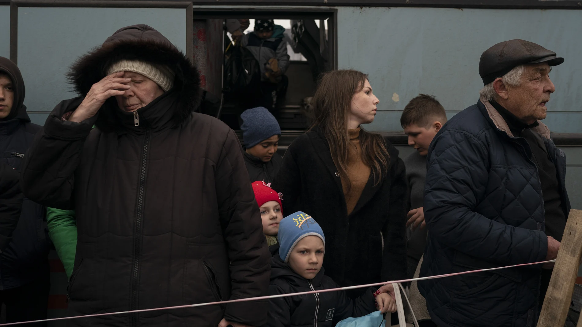 Ucranianos de Mariupol se bajan de un autobús en el que se puede leer en ruso: "niños"