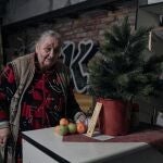 Una anciana sonríe junto a un árbol de Navidad y manzanas y mandarinas, que el capellán Leonid, policía, regaló a la gente, en el sótano de un edificio de apartamentos utilizado como refugio antiaéreo en Avdiivka, región de Donetsk