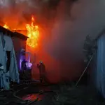 Los bomberos extinguen un incendio en una tienda de juguetes tras el impacto de cohetes en el centro de Donetsk