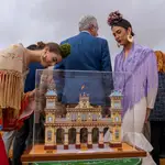 Dos mujeres vestidas de flamencas observan la maqueta de una Portada de la Feria de Sevilla