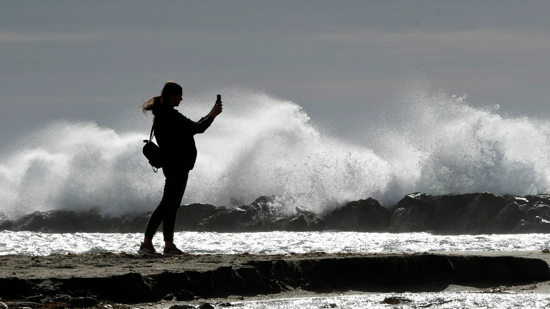 Una persona fotografía las olas en la playa almeriense de El Zapillo