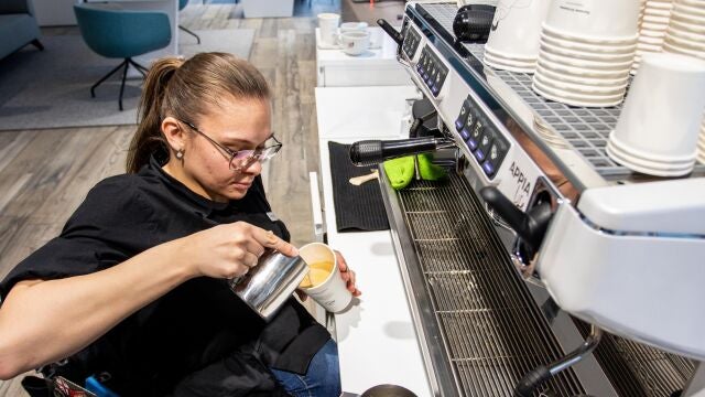 Una persona discapacitada en silla de ruedas trabaja como barista en una cafetería inclusiva