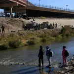 Migrantes caminan en una orilla del Río Bravo ante el operativo implementado por la Guardia Nacional de EE UU en la frontera con Ciudad Juárez, Chihuahua (México)