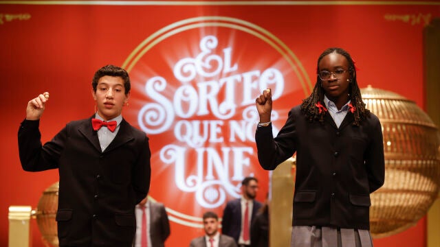 Las estudiantes de San Ildefonso Elisabeth Obarisiagbon Iyamu (d) y su compañero Ilyas Akrouh (i) cantan un quinto premio. EFE/ Javier Lizón