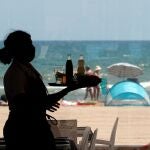 Una camarera lleva una bandeja en la playa valenciana de la Malvarrosa