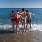 Unos jóvenes se bañan en la playa de la Barceloneta, a 25 de diciembre de 2022, en Barcelona, Cataluña (España).