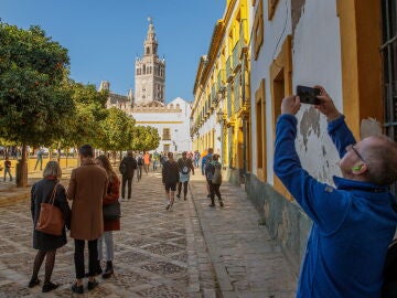 Turistas pasean y hacen fotos en el Patio Banderas junto a la Catedral y la Giralda de Sevilla