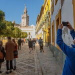 Turistas pasean y hacen fotos en el Patio Banderas junto a la Catedral y la Giralda de Sevilla