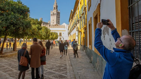 Turistas pasean y hacen fotos en el Patio Banderas junto a la Catedral y la Giralda de Sevilla