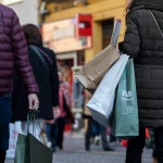 Varias personas con bolsas de la compra en una calle céntrica de Sevilla