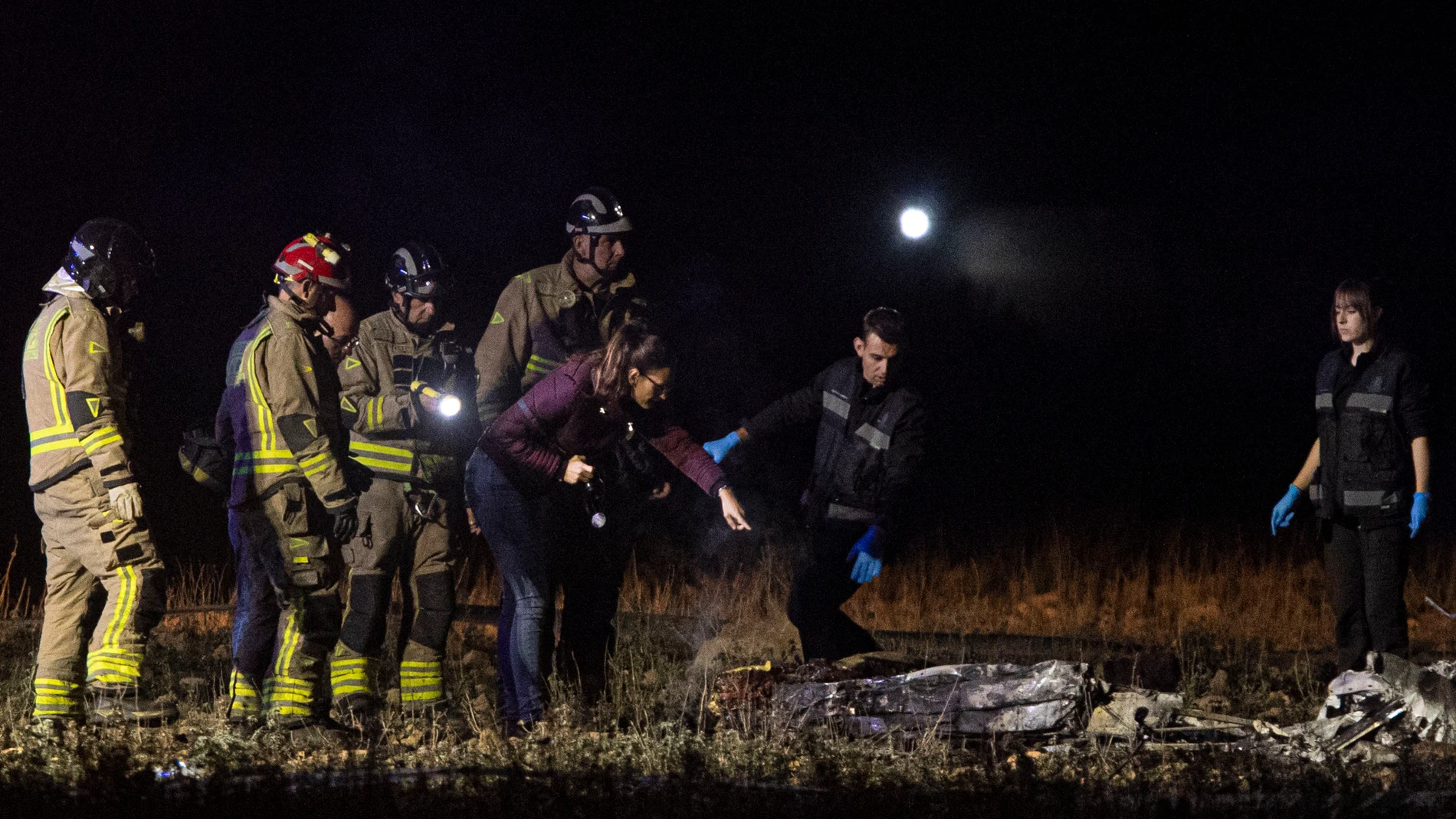 Bomberos y agentes de la Guardia Civil inspeccionan el lugar donde dos hombres de 54 y 47 años, han fallecido este jueves al estrellarse la avioneta biplaza