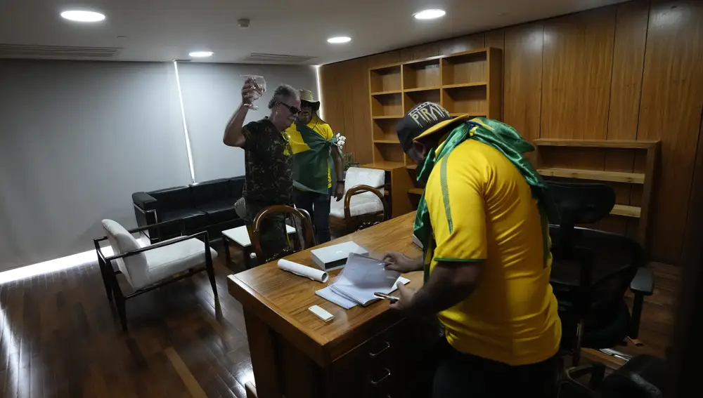 Manifestantes, partidarios del expresidente de Brasil Jair Bolsonaro, rebuscan entre papeles en un escritorio tras irrumpir en el Palacio de Planalto en Brasilia, Brasil