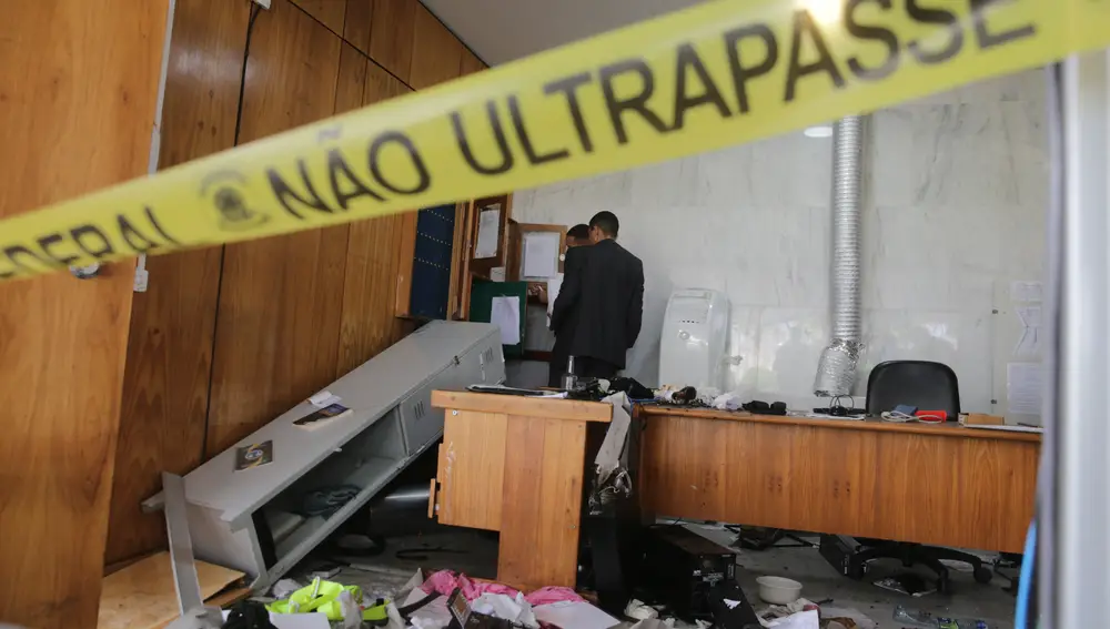 Dos hombres revisan una oficina destrozada al interior del Palacio de Planalto después de que manifestantes bolsonaristas lo invadieran | Fuente: EFE/ André Coelho