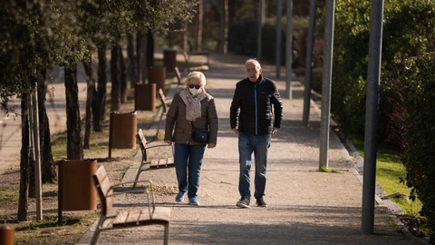 Dos jubilados pasean por un parque de Moratalaz (Madrid)