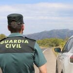 Un agente de la Guardia Civil junto a un vehículo en una carretera. GUARDIA CIVIL
