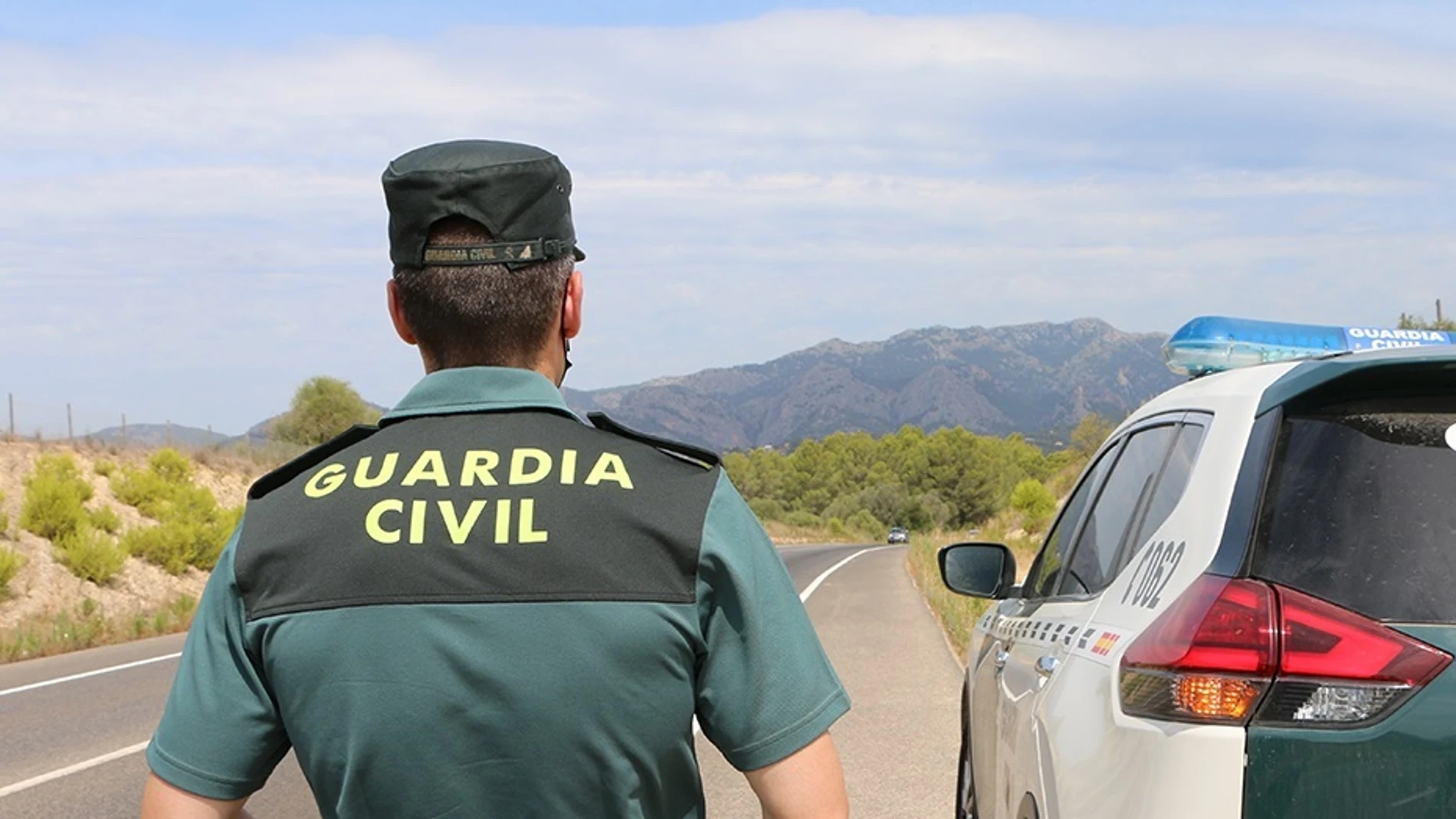 Un agente de la Guardia Civil junto a un vehículo en una carretera. GUARDIA CIVIL