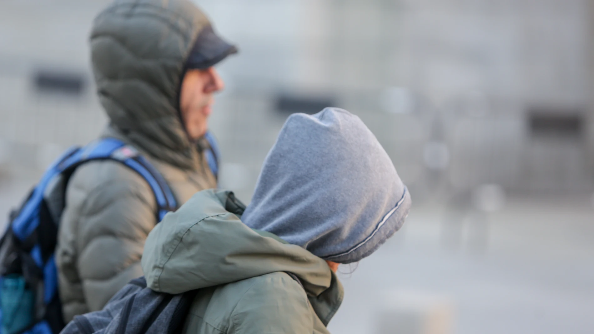 Dos jóvenes se protegen del frío con abrigos y gorros mientras pasean