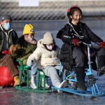 La gente disfruta de una pista de hielo al aire libre de temporada en el lago congelado Shichahai en Pekín, China