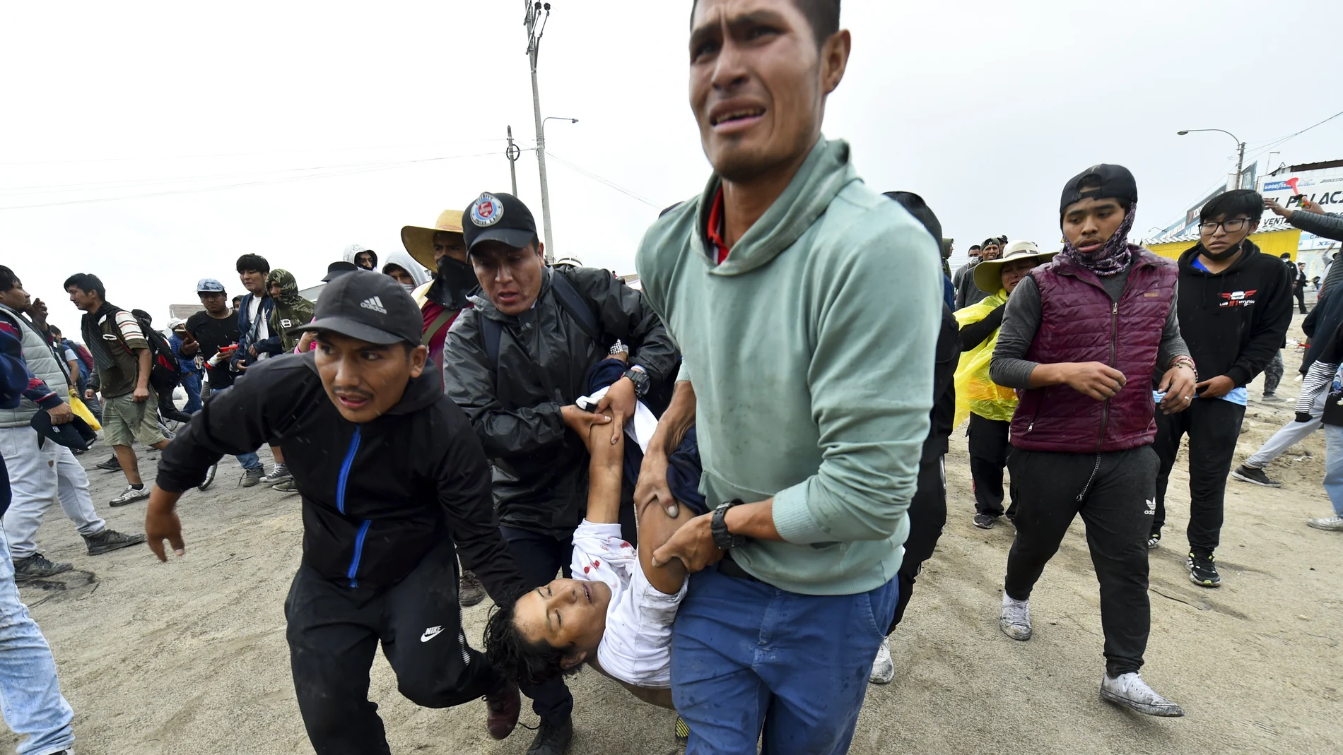 Varios hombres trasladan a un herido en los enfrentamientos con la Policía en Arequipa (Perú)