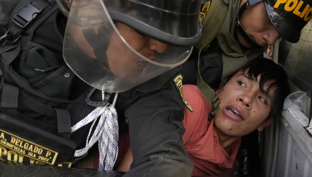 Un manifestante antigubernamental que viajó a la capital desde todo el país para marchar contra la presidenta peruana Dina Boluarte, es detenido y arrojado a la parte trasera de un vehículo policial durante los enfrentamientos en Lima