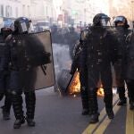 Policias antidisturbios junto a un contenedor quemado en París durante la manifestación
