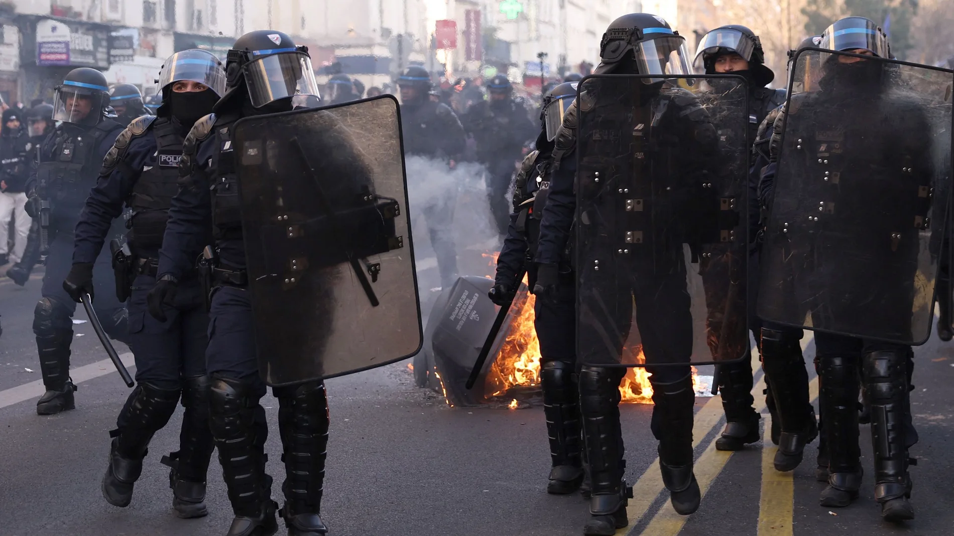 Policias antidisturbios junto a un contenedor quemado en París durante la manifestación