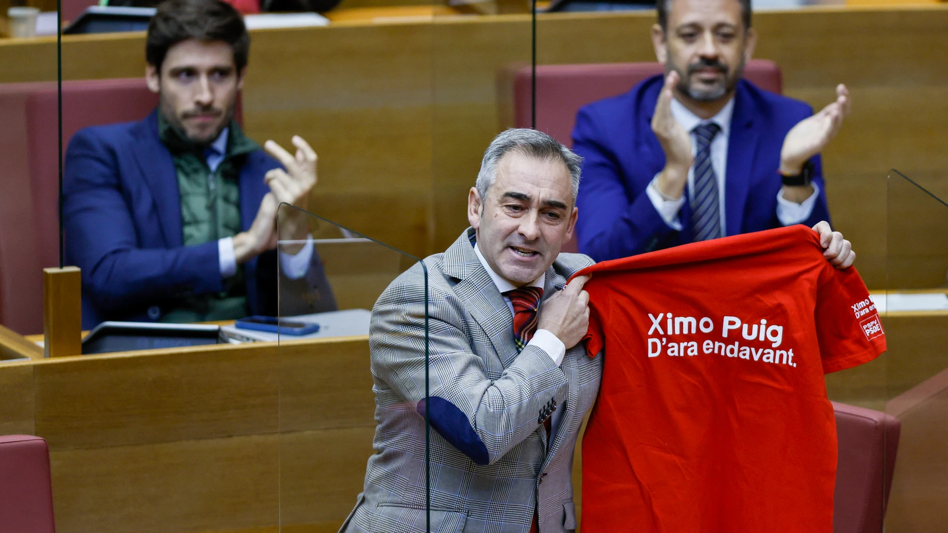 El diputado del PP, Miguel Barrachina, muestra la camiseta que dice: "Ximo Puig. D' ara endavant"