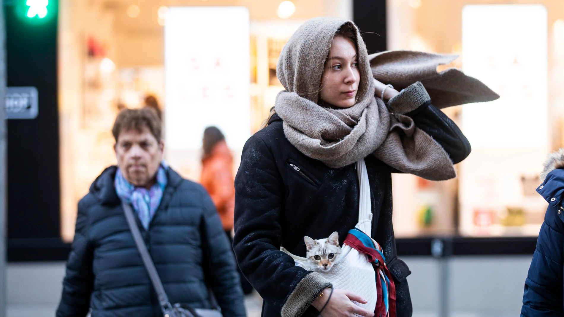 Imagen de una chica que porta un gato, arropados con una bufanda por las bajas temperaturas en la capital