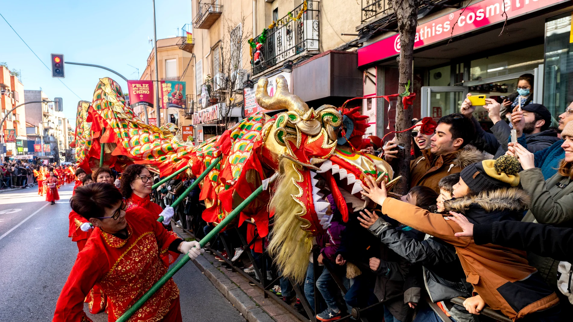 Varias personas acercan un dragón a la gente durante la celebración del pasacalles del Año Nuevo Chino 2023, en el distrito de Usera