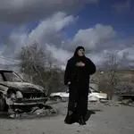 Una mujer palestina junto a un coche quemado en el pueblo de Jalud, cerca de la ciudad cisjordana de Naplusa