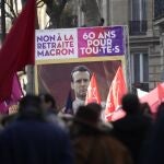 Manifestantes sostienen un cartel que muestra al presidente francés Emmanuel Macron y en el que se lee "No al plan de jubilación de Macron, 60 años para todos"