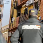 Un agende de Policía Nacional miran en dirección a la vivienda que ha sufrido el incendio en Huelva