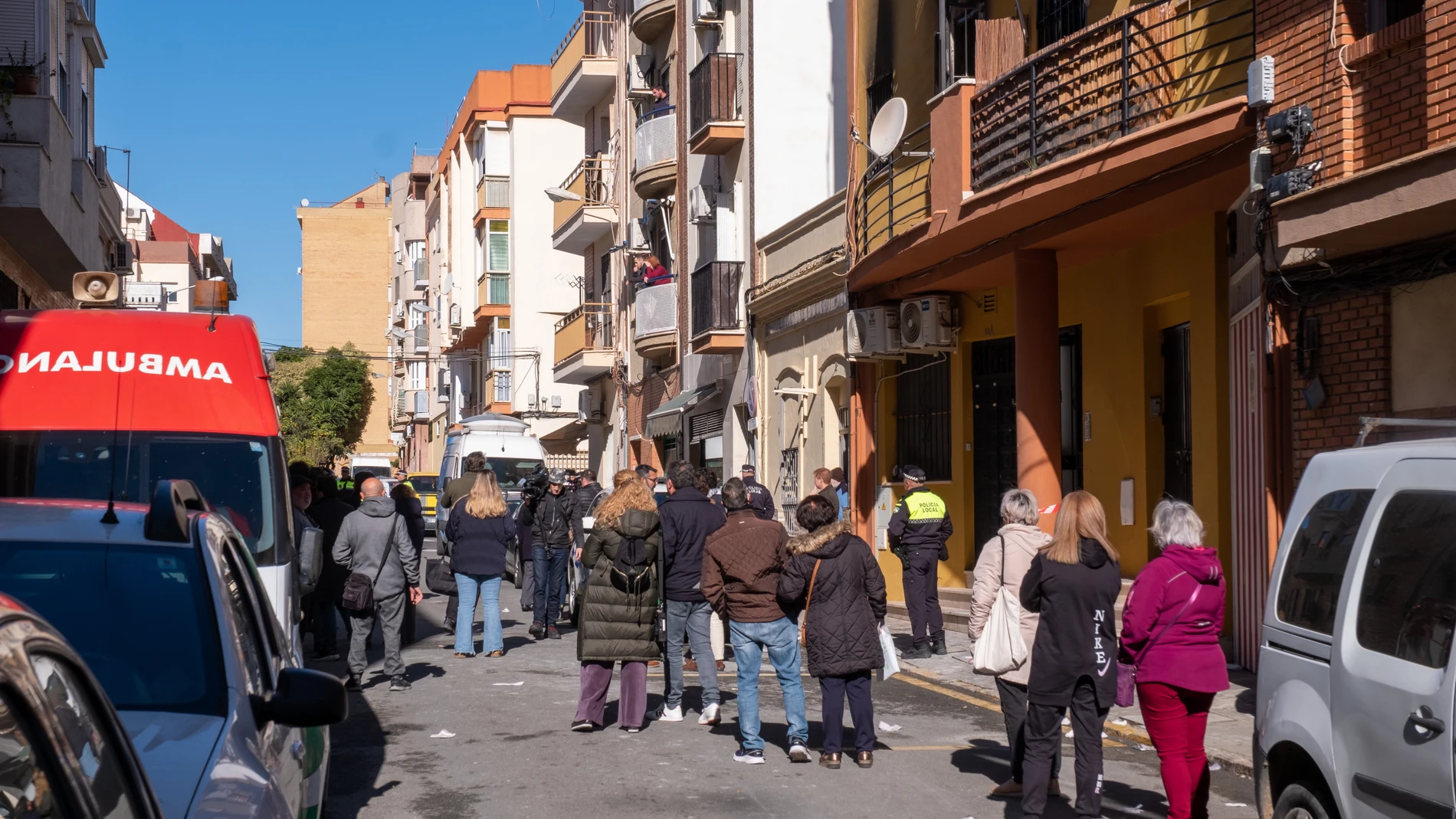 Vecinos, efectivos sanitarios y fuerzas de seguridad en la calle junto al bloque de viviendas de la calle Villanueva de los Castilleja, en la barriada de Isla Chica en Huelva