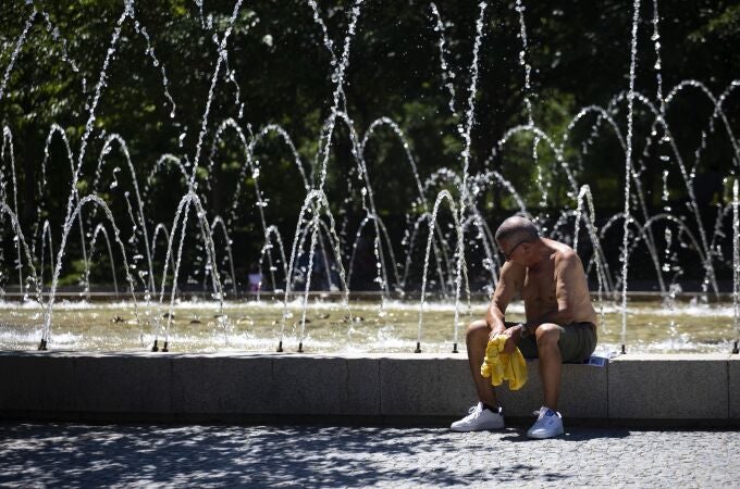 Un hombre descansa al lado de una fuente durante una de las olas de calor en Madrid 