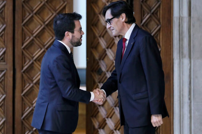 El presidente de la Generalitat, Pere Aragonès, saluda al líder del PSC, Salvador Illa (d), a su llegada al Palau de la Generalitat para la firma del acuerdo